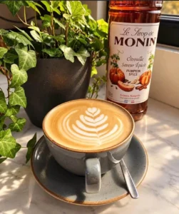 Pumpkin Spiced Latte in front of flowerpot and a bottle of Monins Pumpkin Spice
